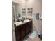 Bathroom features double sinks, dark cabinetry, granite counters, and decorative wall art at 14618 Scottburgh Glen Dr, Wimauma, FL 33598