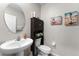 A charming half bathroom features a pedestal sink, wood cabinet, and beach-themed art at 14618 Scottburgh Glen Dr, Wimauma, FL 33598