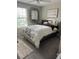 Light-filled bedroom offers a decorative mirror, a patterned bedspread, and cozy gray carpeting at 14618 Scottburgh Glen Dr, Wimauma, FL 33598