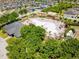 Aerial view of a community pool surrounded by trees, a clubhouse, sun loungers and playground at 14618 Scottburgh Glen Dr, Wimauma, FL 33598