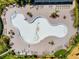An aerial shot shows a unique empty community pool with surrounding palm trees and lounge chairs at 14618 Scottburgh Glen Dr, Wimauma, FL 33598