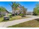 Attractive home exterior featuring a landscaped yard, mature trees, and a paved sidewalk at 14618 Scottburgh Glen Dr, Wimauma, FL 33598