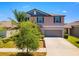 Exterior of a charming two-story home featuring a gray roof, pastel-colored siding and a two-car garage at 14618 Scottburgh Glen Dr, Wimauma, FL 33598