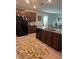 Well-lit kitchen features dark wood cabinetry, granite counters, and stainless steel appliances at 14618 Scottburgh Glen Dr, Wimauma, FL 33598