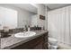 Well-lit bathroom with a single sink vanity featuring granite countertops, complemented by a toilet and shower at 15613 Charr Island St, Sun City Center, FL 33573