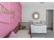 Well-decorated Bedroom featuring a pink accent wall, a stylish crib, and a changing table with a round mirror at 15613 Charr Island St, Sun City Center, FL 33573