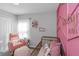 Charming Bedroom with pink accents, featuring a crib and cozy rocking chair at 15613 Charr Island St, Sun City Center, FL 33573