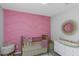 Bright Bedroom with a textured pink accent wall, a crib, and a changing table with decorative elements at 15613 Charr Island St, Sun City Center, FL 33573