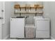 Well-organized laundry room with stylish wallpaper, open shelving, and a washer and dryer at 15613 Charr Island St, Sun City Center, FL 33573