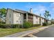 A charming condo building with tan stucco, brown balconies, well-maintained landscaping, and a glimpse of a palm tree at 2087 Hunters Glen Dr # 126, Dunedin, FL 34698