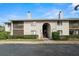 A two-story condominium building with a stucco exterior, chimneys, and mature landscaping near the entrance at 2087 Hunters Glen Dr # 126, Dunedin, FL 34698