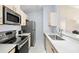 Galley-style kitchen featuring stainless steel appliances, light countertops, and ample cabinet space at 2087 Hunters Glen Dr # 126, Dunedin, FL 34698