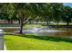 Scenic pond view featuring a fountain, lush green grass, and mature trees, creating a tranquil and picturesque setting at 2087 Hunters Glen Dr # 126, Dunedin, FL 34698