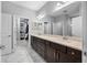 Bright bathroom featuring double vanity, large mirror, and walk-in closet for storage at 2270 Spring Lake Ct, Clearwater, FL 33763