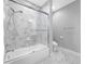 Modern bathroom featuring a bathtub with glass enclosure and marble-look tile at 2270 Spring Lake Ct, Clearwater, FL 33763