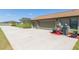 View of a 3-car garage with an extended driveway, potted plants, and well-manicured lawn at 27941 Austin Woods Dr, Dade City, FL 33525