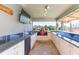 Outdoor kitchen under a covered patio, featuring modern appliances and a grill at 27941 Austin Woods Dr, Dade City, FL 33525