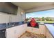 Outdoor kitchen featuring a grill, sink, mini fridge, television and granite countertops at 27941 Austin Woods Dr, Dade City, FL 33525