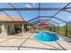 Screened-in pool featuring a red umbrella, patio, an outdoor kitchen, and green landscaping at 27941 Austin Woods Dr, Dade City, FL 33525