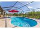 The screened-in pool features a red umbrella, patio, and lush green landscaping at 27941 Austin Woods Dr, Dade City, FL 33525
