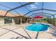 Screened-in pool with an outdoor kitchen, patio, and lush green landscaping at 27941 Austin Woods Dr, Dade City, FL 33525