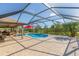 A screened-in pool with patio, a tiki bar, outdoor kitchen, lounge chairs and green landscaping at 27941 Austin Woods Dr, Dade City, FL 33525