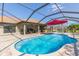 A blue swimming pool with patio, outdoor kitchen, sun umbrella, and green landscaping at 27941 Austin Woods Dr, Dade City, FL 33525