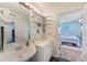 Bathroom featuring a pedestal sink, decorative shelves, and a view into an adjacent bedroom at 300 Promenade Dr # 106, Dunedin, FL 34698