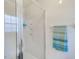 All-white shower enclosure with glass door, tiled walls, and a towel bar, showcasing a clean design at 300 Promenade Dr # 106, Dunedin, FL 34698