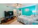 Spacious bedroom features starfish-themed bed, ceiling fan, TV, and glimpses of the en suite bathroom at 300 Promenade Dr # 106, Dunedin, FL 34698