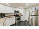 Modern kitchen with stainless steel appliances, white cabinets and tile flooring at 300 Promenade Dr # 106, Dunedin, FL 34698