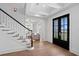 Bright foyer with hardwood floors, a staircase, and modern black doors leading to the outside at 3801 Bayshore Blvd, Tampa, FL 33611