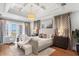 A bright main bedroom with a tray ceiling, hardwood floors, view and seating area; an inviting relaxing space at 3801 Bayshore Blvd, Tampa, FL 33611
