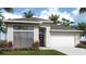 Modern home featuring sleek lines, stone accents, a gray roof, and lush landscaping, providing curb appeal at 413 Sun Chaser Dr, Nokomis, FL 34275
