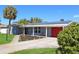 Charming single-story home featuring solar panels, a red garage door, and lovely landscaping at 4301 50Th S Ter, St Petersburg, FL 33711