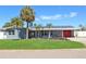 Charming single-story home with well-manicured lawn, palm trees, and solar panels against a clear blue sky at 4301 50Th S Ter, St Petersburg, FL 33711
