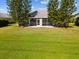 Home's backyard featuring lush green grass and mature trees surrounding a charming home with a screened lanai at 4320 Northampton Dr, New Port Richey, FL 34653