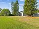 View of the backyard with green grass and mature trees plus a screened-in lanai area attached to the home at 4320 Northampton Dr, New Port Richey, FL 34653