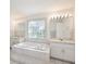 Bathroom featuring a tiled step-up tub with dual sinks and a glass block window at 4320 Northampton Dr, New Port Richey, FL 34653