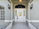 Close-up of an inviting front door, featuring decorative glass and elegant sconces at 4320 Northampton Dr, New Port Richey, FL 34653