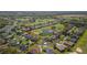 Wide aerial view of community homes situated on a golf course with mature trees and water features at 11013 Moshie Ln, San Antonio, FL 33576