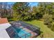 Backyard view of a screened-in pool surrounded by lush greenery and a well-maintained lawn at 18312 Pleasant Ridge Pl, Lutz, FL 33548