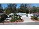 Home showcasing a well-manicured front yard with palm trees, hardscape, and a paved driveway at 201 79Th Ne Ave, St Petersburg, FL 33702