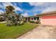 Beautiful home exterior with lush green lawn, tropical plants, and a bright pink garage door at 2340 W Bay Isle Se Dr, St Petersburg, FL 33705