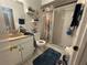 Compact bathroom with a shower, vanity, shelving, tile walls, and decorative elements at 3111 W Spruce St, Tampa, FL 33607