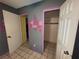 Bedroom featuring grey walls with colorful geometric decorations, tiled flooring, and open closet with yellow wall paint at 3111 W Spruce St, Tampa, FL 33607