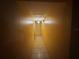 Narrow hallway illuminated by a pendant light fixture, showcasing tiled floors and yellow painted walls at 3111 W Spruce St, Tampa, FL 33607