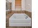 Bright bathroom showcasing a soaking tub with tiled surround and a window with wood blinds at 3303 Ranchdale Dr, Plant City, FL 33566