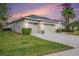 Single-story home shows a three-car garage, beautiful landscaping, and a well-kept lawn at sunset at 3417 Diamond Falls Cir, Land O Lakes, FL 34638