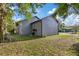 A spacious, grassy backyard includes an AC unit and is shaded by mature trees at 3902 E Henry Ave, Tampa, FL 33610